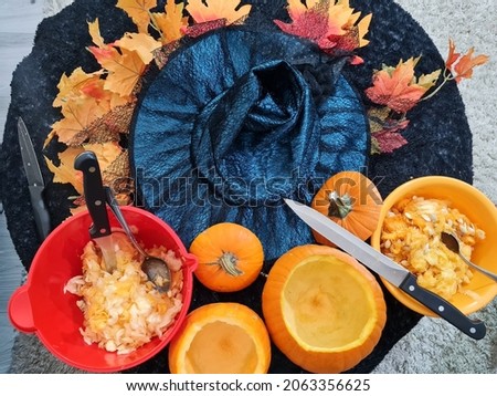 picture of harvesting or selecting seeds from halloween pumpkins. cooking. healthy and vitamin vegetables. autumn. october 31. knifes and bowls on round table. colorful leaves.