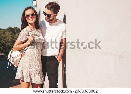 Smiling beautiful woman and her handsome boyfriend. Woman in casual summer clothes. Happy cheerful family. Female having fun. Couple posing on the street background in sunglasses.Hugging each other