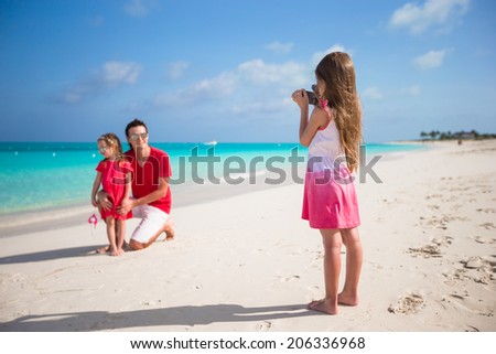 Little girl making photo on phone of her family at the beach