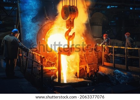 Process of casting in foundry, liquid molten metal pouring in ladle. Heavy metallurgy industry Royalty-Free Stock Photo #2063377076