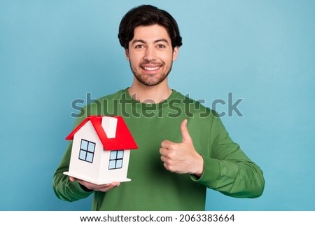Photo of young nice smiling handsome guy showing thumb-up hold little home moving isolated on blue color background