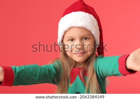 Cute little girl dressed as elf on color background