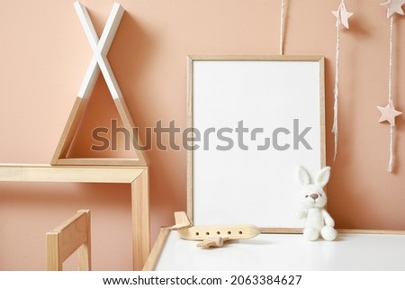Interior of modern children's room with blank frame on table
