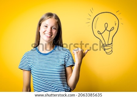 Beautiful caucasian woman pointing thumb up to the side, blonde female caucasian smiling happy with open mouth, finding ideas concept
