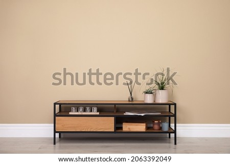 Modern TV cabinet with decor near beige wall. Space for design Royalty-Free Stock Photo #2063392049