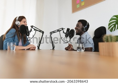 Multiracial people recording a podcast using microphone and headphones from home studio