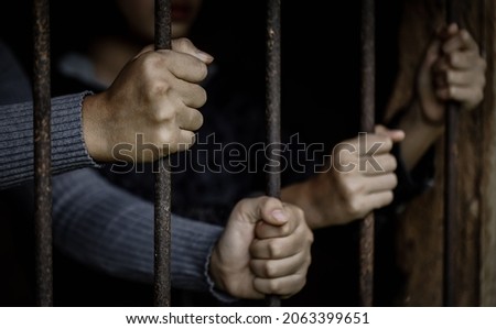 Hands holding a steel cage in old iron bar. Restriction of the rights of human. Royalty-Free Stock Photo #2063399651