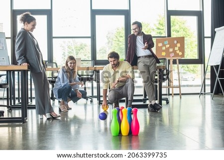 Positive interracial business people playing bowling in office