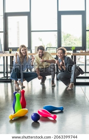 Positive multiethnic business people playing bowling in office