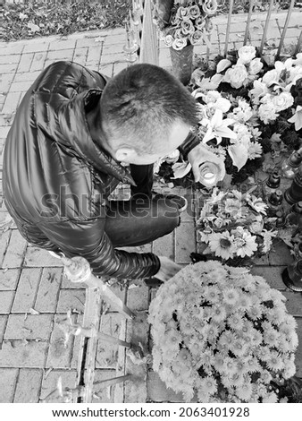 attractive man lighting candles at cemetery. boy celebrating all saints day. november 1. autumn holidays. souls. memories