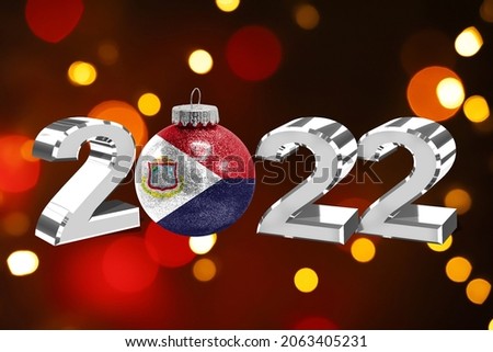 Colorful blurred background and applied the flag of Saint Martin on the New Year's toy. New Year 2022 Celebration