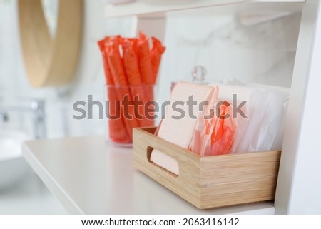 Organizer with tampons and menstrual pads on shelving unit in bathroom. Feminine hygiene products Royalty-Free Stock Photo #2063416142