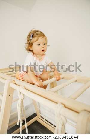 Baby girl play with developmental wooden structure at home or kindergarten or daycare center