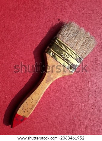 a photo of a paint brush placed in red cement