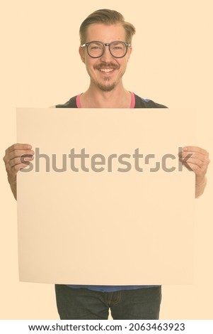 Studio shot of young handsome bearded Scandinavian man as nerd isolated against white background