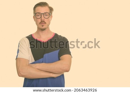 Studio shot of young handsome bearded Scandinavian man as nerd isolated against white background