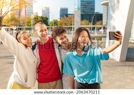 Cheerful young people taking group selfie on the city street. Multicultural friends.