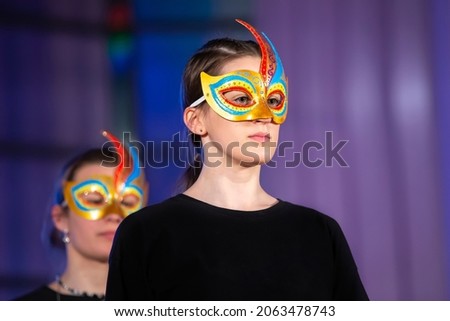 The face of a girl in a theatrical mask on a dark background.
