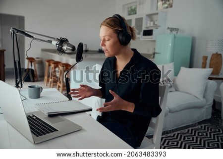 Caucasian female business woman recording podcast from home with technical equipment