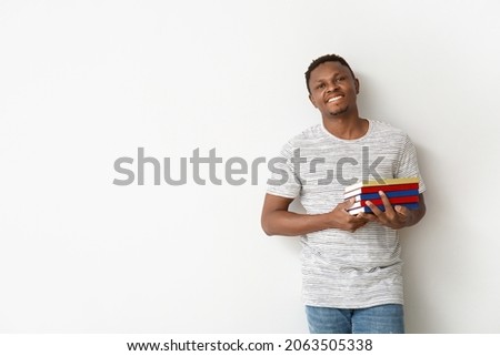 African-American man with books on light background
