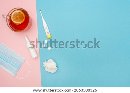 Catch a cold. Flu season. Disease. Flat lay. Medical mask, pills, nasal spray, used wipes, thermometer, and lemon tea. Place for your text. Copy space. Mockup. Seasonal cold concept.  Royalty-Free Stock Photo #2063508326