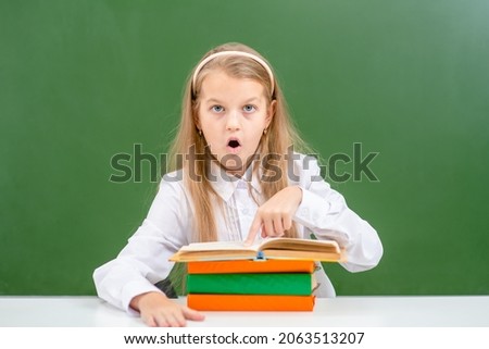 Shocked girl looks at book in classroom
