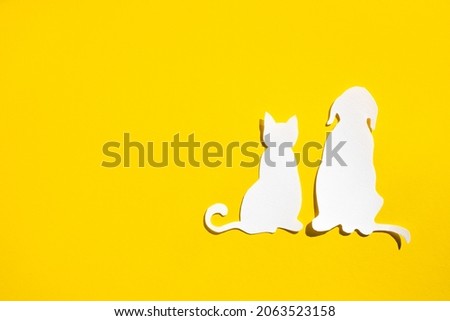 Paper silhouette of a cat and dog on a yellow background. Flat lay, place for text. Veterinary or animal care.