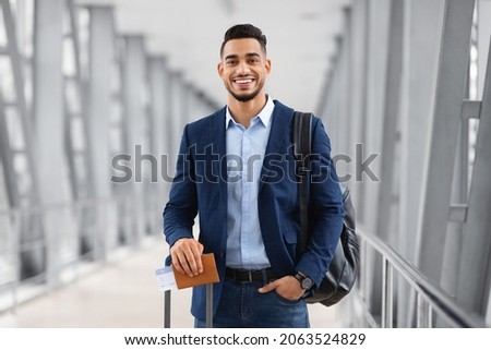 Portrait Of Young Middle Eastern Male Traveller Posing At Airport, Handsome Arab Man With Luggage, Passport And Tickets Smiling At Camera While Waiting For Flight In Terminal, Copy Space Royalty-Free Stock Photo #2063524829