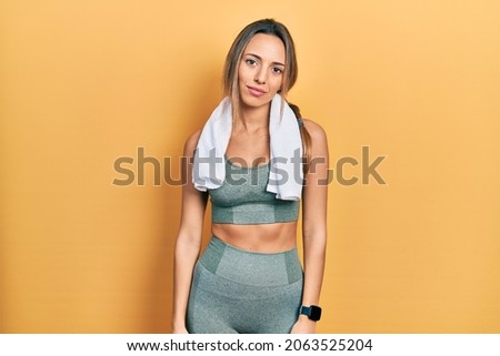 Beautiful hispanic woman wearing sportswear and towel looking sleepy and tired, exhausted for fatigue and hangover, lazy eyes in the morning. 