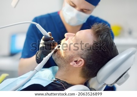 Dentist and patient at medical center. Doctor treats a mature man teeth with dental drill. Orthodontist and prosthetics appointment. Hygiene and teeth healthy. Royalty-Free Stock Photo #2063526899