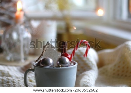 Mug filled with various Christmas decorations, soft blanket and lit candles. Hygge at home. Selective focus.
