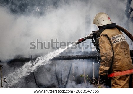  Firefighters with the inscription on the back in Russian "Fire protection" extinguish the fire on the fire Royalty-Free Stock Photo #2063547365