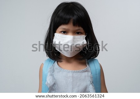 Portrait of Asian girl kid with protective face mask and school backpack ready for new school year with pandemic restrictions. Concept of kid going back to school and new normal lifestyle