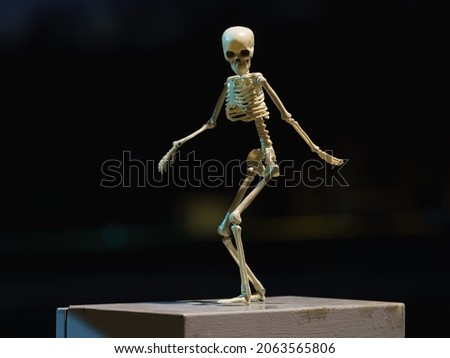 Photograph of a skeleton on a city street at night. Dancing skeleton toy. Natural dark  background. He having fun. Halloween concept.