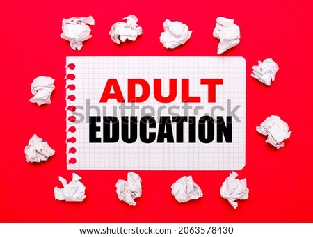 On a bright red background, white crumpled sheets of paper and a sheet of paper with the text ADULT EDUCATION