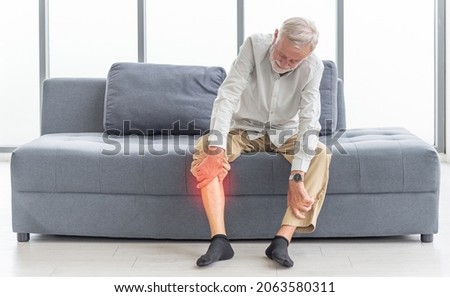 Health care and problem concept  Uhappy senior man suffering from knee ache at home. Knee joint injury. Gout. Rheumatoid. Arthritis. Osteoporosis Royalty-Free Stock Photo #2063580311