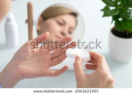 A woman holds a contact lens on her finger Royalty-Free Stock Photo #2063621405