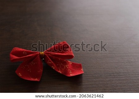Left side red bow on wooden table.