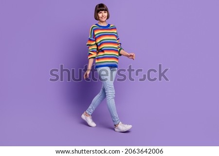 Photo of pretty cheerful positive lady walk travel wear striped pullover jeans shoes isolated violet color background
