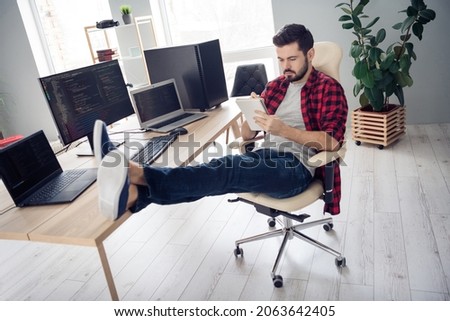 Full length photo of serious young man sit desk write notebook programmer coder indoors inside office