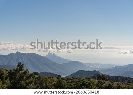 Mountainous landscape, with silhouettes of mountains in the background, with some clouds.