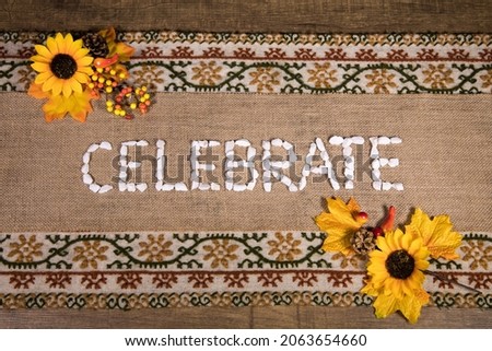 Celebrate written with white stones over a burlap banner with yellow flowers and a handcrafted table runner