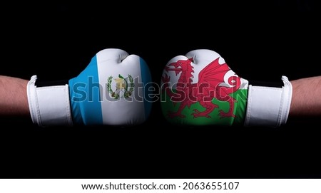 Two hands of wearing boxing gloves with Wales and Guatemala flag. Boxing competition concept. Confrontation between two countries