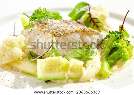Roasted cod with mashed potatoes and broccoli. White fish fillet with skin with vegetables isolated on white background. Healthy food in restaurant menu. Fish and cabbages in minimalism style