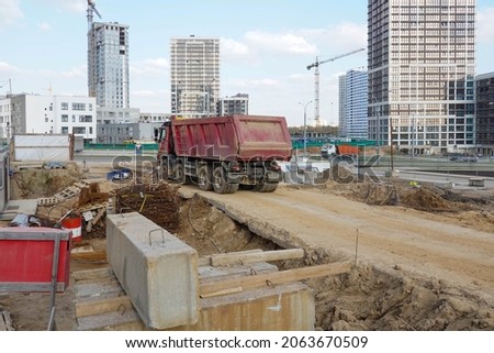 Photo of a truck at the construction site of multi-storey buildings in the city.