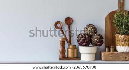 Modern composition on the kitchen interior with vegetables cutting board, food, herbs, kitchen accessories and copy space on the shelf.