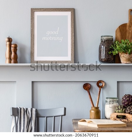 Interior design of kitchen space with mock up photo frame, wooden table, herbs, vegetables, fruits, food and kitchen accessories in modern home decor.