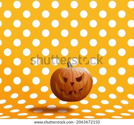 Carved Halloween pumpkin on orange background with polka dots.