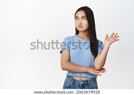 Annoyed arrogant asian woman roll eyes, looking away and wave hand to decline smth bothering her, standing over white background Royalty-Free Stock Photo #2063674928
