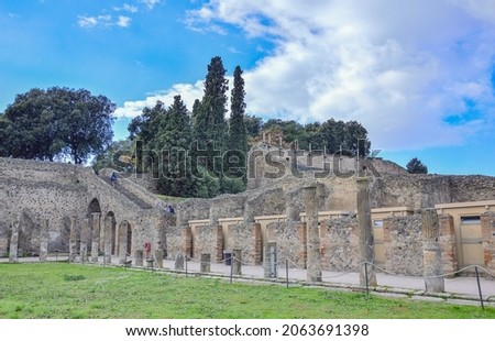 Blue sky with clouds over the ruined wall of the theatre in the ancient Roman city of Pompeii and mount Vesuvius, Italy